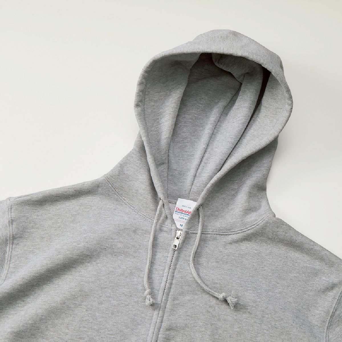 The hood has no front seam, making it printable; the hood drawstring is a round cord in the same color as the body.