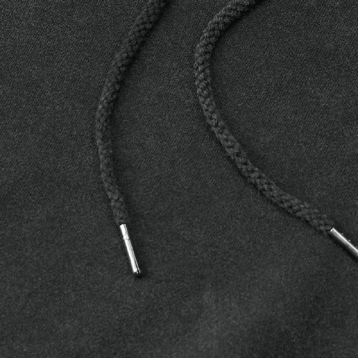 The hood drawstring is a round cord in the same color as the body, with metal tips at the ends.