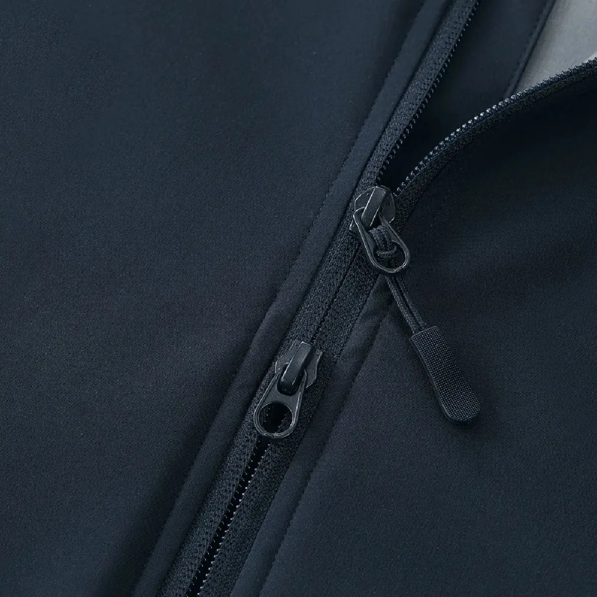 The front features a double-slider synthetic resin coil zipper, designed for reverse use, with a zipper pull tab and an overhang to prevent cold air from entering.