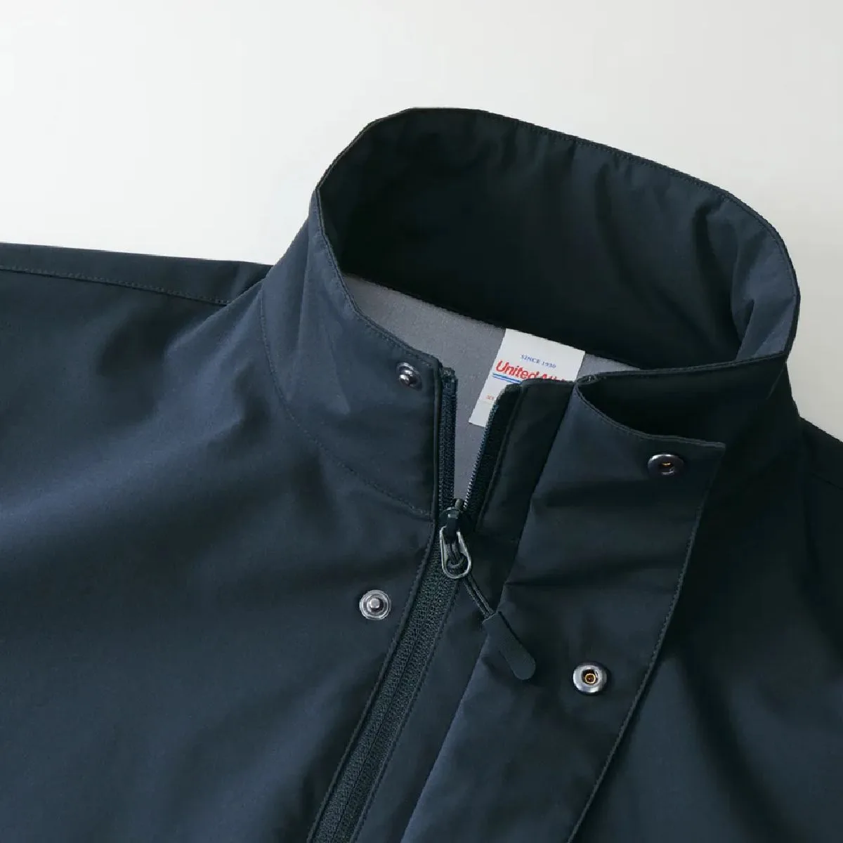 The collar is a stand collar, the front has a fly front (placket) to prevent cold air from entering, and it has metal snap buttons.